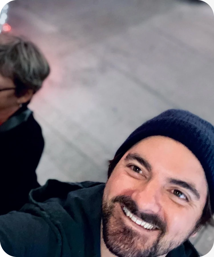 Eric smiling in a beanie beside family