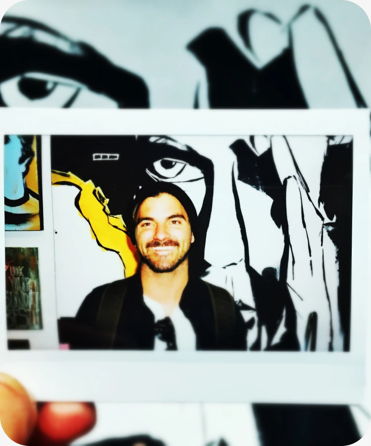 A photo of a photo of Eric, held up against a graphic mural